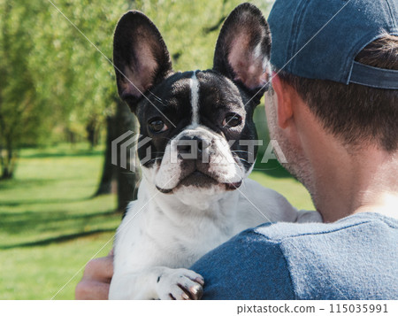 Attractive man holding a puppy in the park Attractive man holding a puppy in the park 115035991