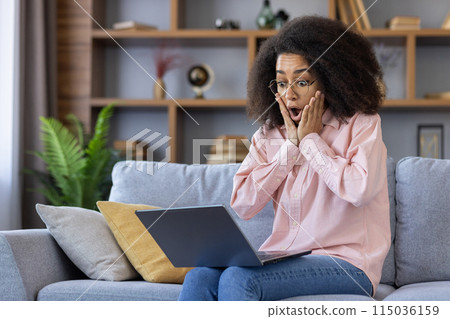 Woman in casual attire expressing shock and surprise while looking at her laptop screen at home Woman in casual attire expressing shock and surprise while looking at her laptop screen at home 115036159