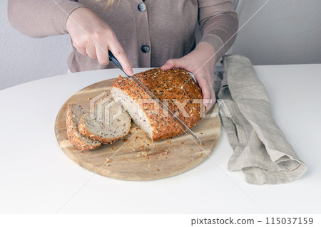 Woman cutting bread on a cutting board. 115037159