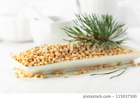 Peeled pine nuts on a white wooden table. Peeled pine nuts on a white wooden table. 115037300