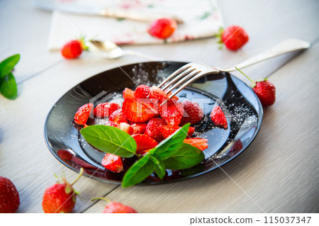 fresh fruit salad of ripe strawberries on a light wooden table 115037347