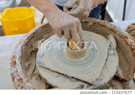 Professional potter worker creating bowl with wet soft clay using potter wheel 115037677
