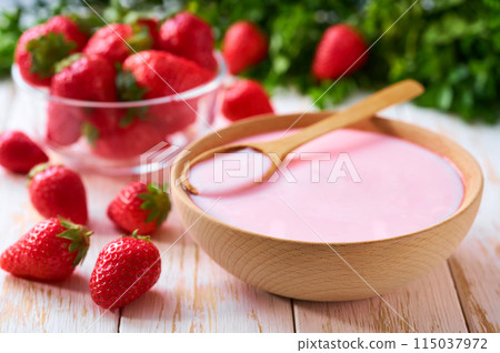 fruit yogurt in a wooden bowl with spoon and fresh strawberry on a light background, selective focus. 115037972