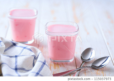 Two portions of homemade strawberry yogurt in a glass jars on a white table, selective focus. 115037973