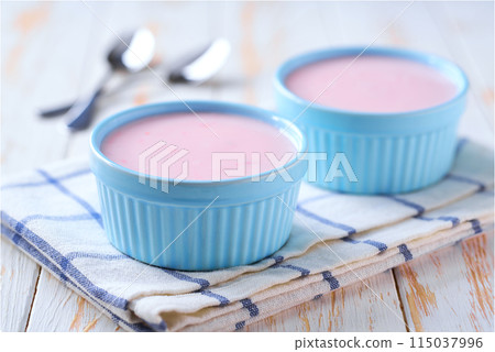 pink smoothie in a ceramic bowl with spoon on a white table, selective focus. 115037996