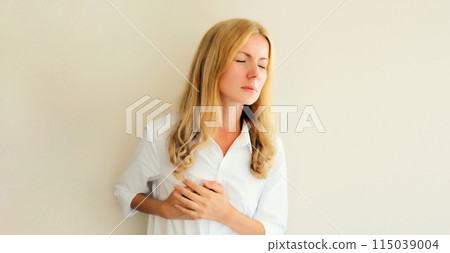 Young woman grabbing put hands on her chest suffering from heart pain, feeling bad with acute pain Young woman grabbing put hands on her chest suffering from heart pain, feeling bad with acute pain 115039004
