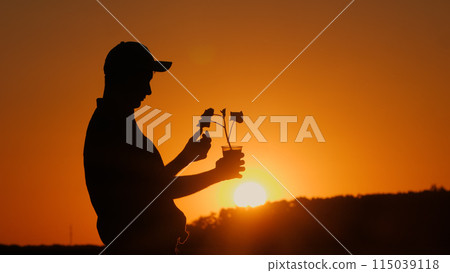 The silhouette of an agronomist holding a pot with a plant ready for planting is visible. 115039118