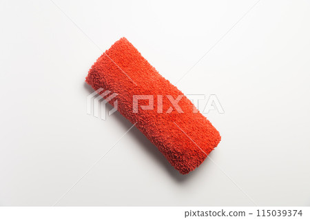 Fluffy orange-red rolled up towel on white background 115039374