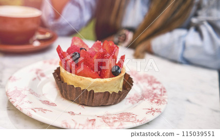Young woman tasting strawberry-topped cake, Selective focus. Young woman tasting strawberry-topped cake, Selective focus. 115039551
