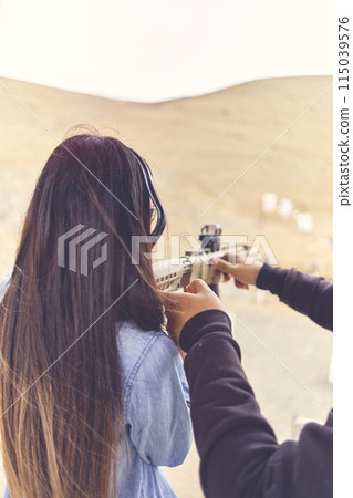 Woman releasing stress, Instructor helping woman with gun Woman releasing stress, Instructor helping woman with gun 115039576