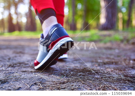 Women's feet in sneakers in the park. Running in nature 115039694