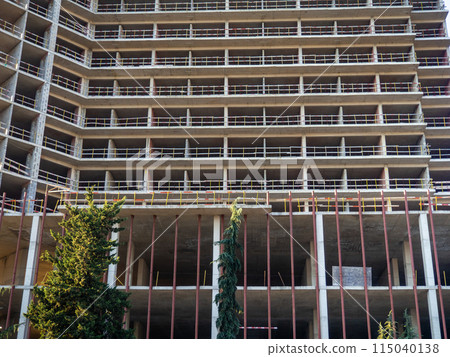 Construction of a modern high house. Building frame. Gray concrete structure. Unfinished house. 115040138
