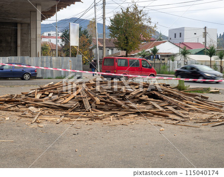 A pile of old boards lies on the street. Used building materials.  Rubbish on the street 115040174