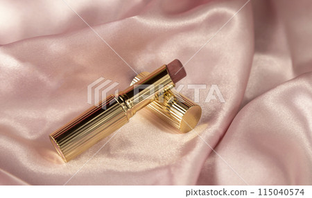 Lipstick on a soft pink silk fabric. Lip care, women's beauty, 115040574