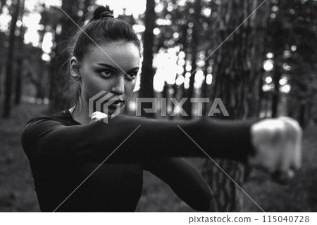 Black and white photo of a woman practicing martial arts in nature. film grain 115040728