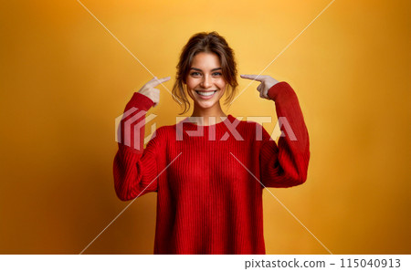 Smiling Young Woman in Red Sweater Pointing at Her Head 115040913