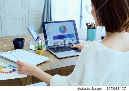 Female designer working at a computer at home Female designer working at a computer at home 115041417