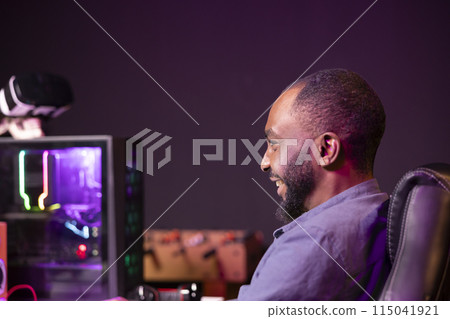 Gamer laughing at home, having fun playing videogames on computer. Joyous african american man contending in gaming tournament using powerful neon lit desktop PC in apartment Gamer laughing at home, having fun playing videogames on computer. Joyous african american man contending in gaming tournament using powerful neon lit desktop PC in apartment 115041921