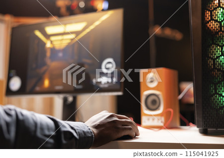 Man in living room playing video games on gaming PC at computer desk, enjoying day off, close up shot. Gamer using mouse to shoot enemies in online multiplayer game from neon lights ornate home Man in living room playing video games on gaming PC at computer desk, enjoying day off, close up shot. Gamer using mouse to shoot enemies in online multiplayer game from neon lights ornate home 115041925