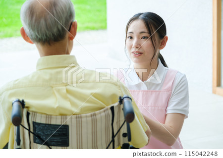 A helper who cares for an elderly person in a wheelchair A helper who cares for an elderly person in a wheelchair 115042248