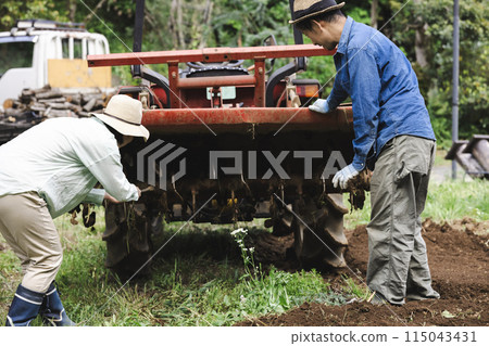 A farmer taking care of a tractor 115043431
