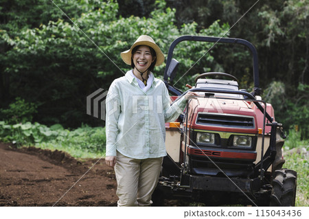 Woman plowing the field with a tractor 115043436