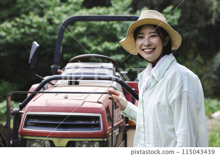 Woman plowing the field with a tractor 115043439