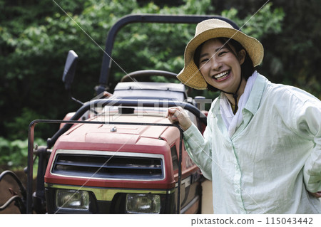 Woman plowing the field with a tractor 115043442