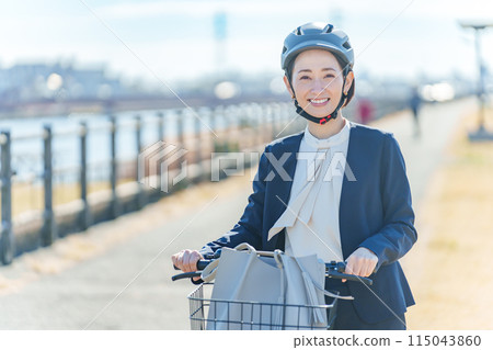 A businessman commuting by bicycle wearing a helmet A businessman commuting by bicycle wearing a helmet 115043860