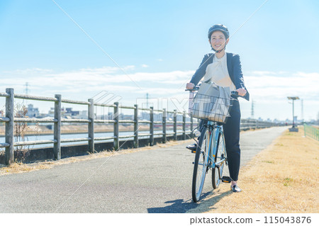 A businessman commuting by bicycle wearing a helmet 115043876