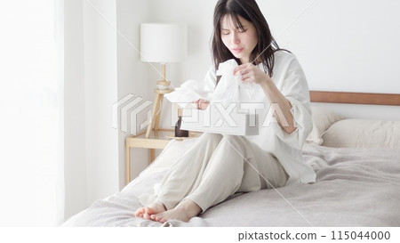 Woman blowing her nose in the room 115044000