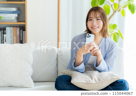 年輕女子在客廳看智慧型手機 115044067