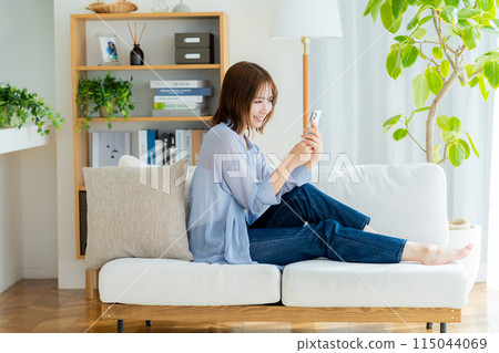 A young woman using a smartphone in the living room A young woman using a smartphone in the living room 115044069