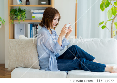 A young woman using a smartphone in the living room 115044072
