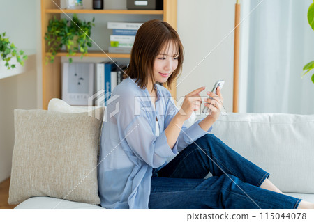 A young woman using a smartphone in the living room 115044078