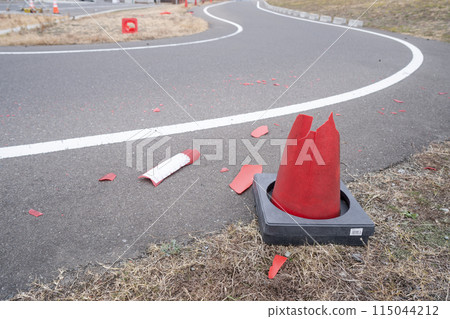 A cone that was damaged after being hit by a car on a curved road A cone that was damaged after being hit by a car on a curved road 115044212