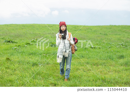 A woman holding a camera in the meadow 115044410