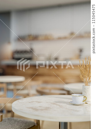 A luxury white marble round table features a coffee cup and a vase in a contemporary coffee shop. 115045475