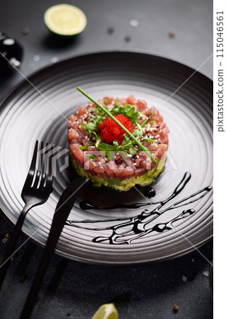 Tuna and avocado tartare on a dark ceramic plate Tuna and avocado tartare on a dark ceramic plate 115046561