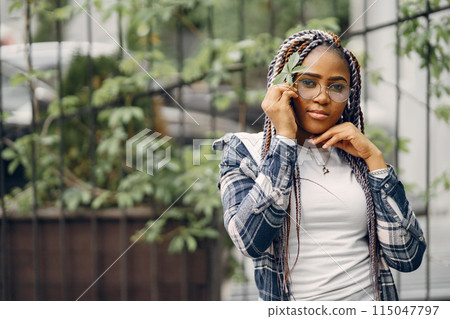 Young black woman with afro hairstyle smiling in urban park. Mixed girl walking in a city. Young black woman with afro hairstyle smiling in urban park. Mixed girl walking in a city. 115047797