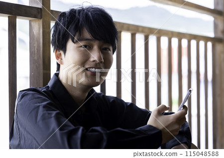 在陽台上使用智慧型手機的年輕人 115048588