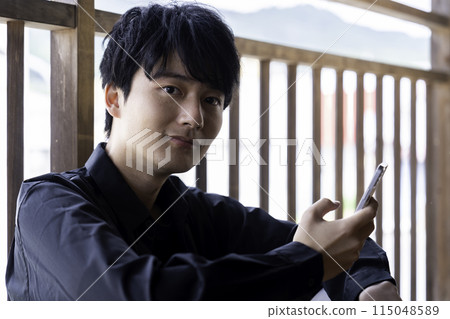 在陽台上使用智慧型手機的年輕人 115048589