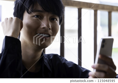 A young man using a smartphone on the balcony A young man using a smartphone on the balcony 115048595