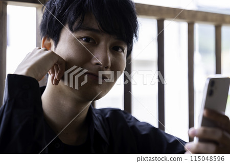 A young man using a smartphone on the balcony 115048596