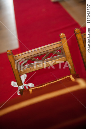 An elegant wooden church pew featuring a red carpet for religious ceremonies and events 115048707