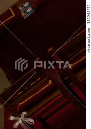 Elegant ceremonial chairs with ribbon adornments in a solemn and prestigious venue Elegant ceremonial chairs with ribbon adornments in a solemn and prestigious venue 115048711