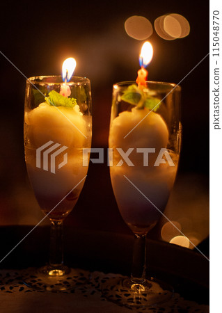 Enhance the romantic atmosphere by serving ice cream candles in elegant champagne glasses 115048770