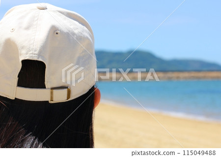 沙灘上一個長髮的女人,望著大海,後腦勺的特寫 沙灘上一個長髮的女人,望著大海,後腦勺的特寫 115049488