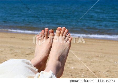 Close-up of a woman's feet on a sandy beach: bare feet and sand Close-up of a woman's feet on a sandy beach: bare feet and sand 115049873
