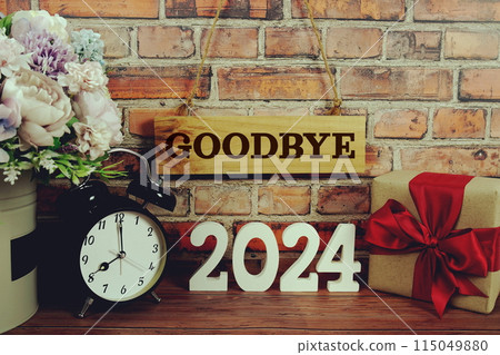 Goodbye 2024 letters with alarm clock and gift box on wooden background 115049880